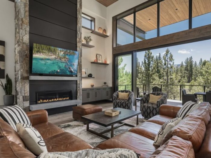 Large living room with cathedral ceilings, leather furniture and views of forests in North Lake Tahoe - vacation rental Alpine Greenside Estate
